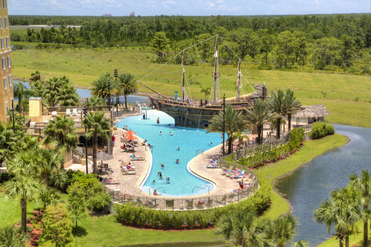Aerial view of the Pirate's Plunge pool with its full-size pirate ship, surrounded by palm trees and family-friendly pools