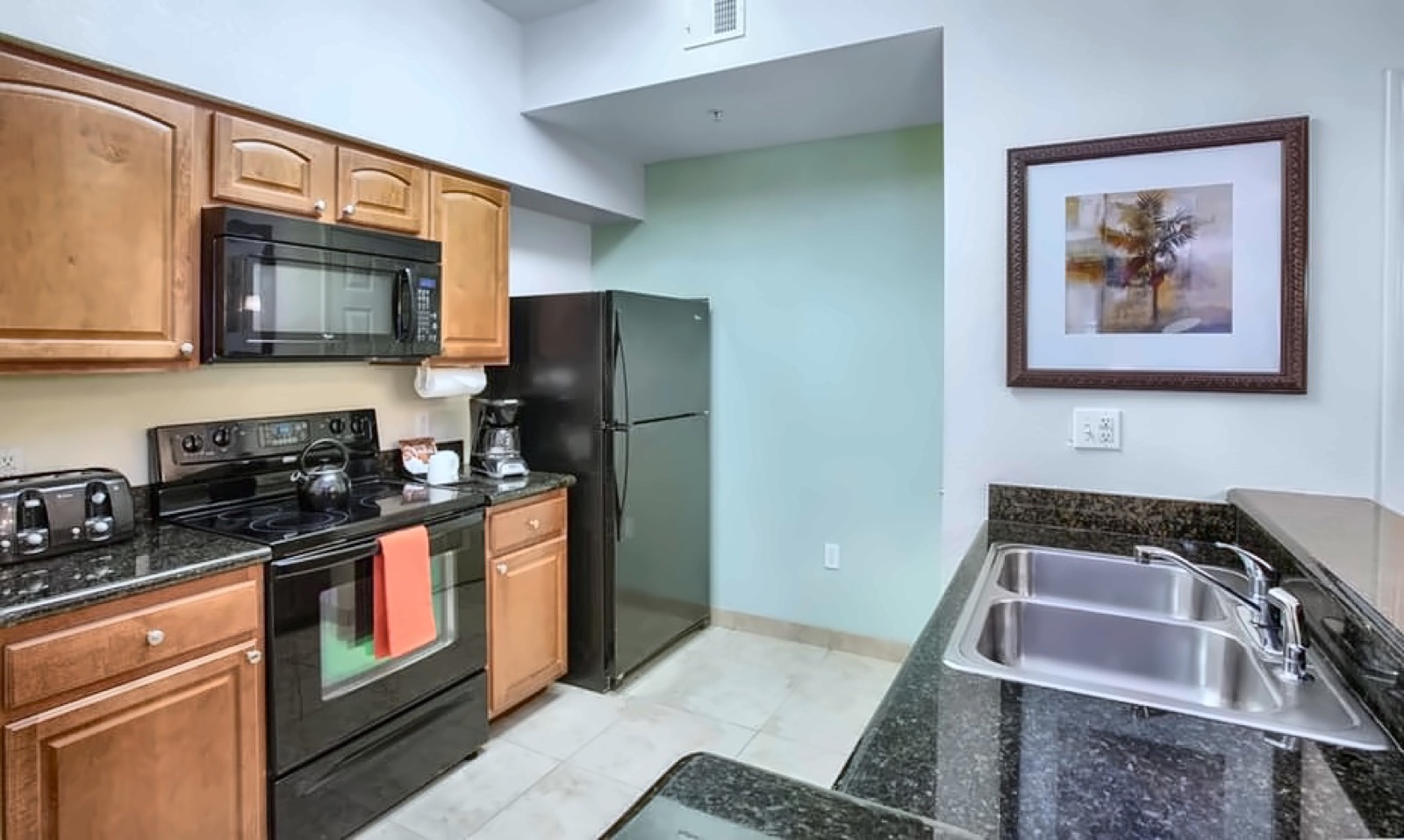 Fully equipped LBV suite kitchen with granite counters, full-size refrigerator, stove, microwave, and double sink